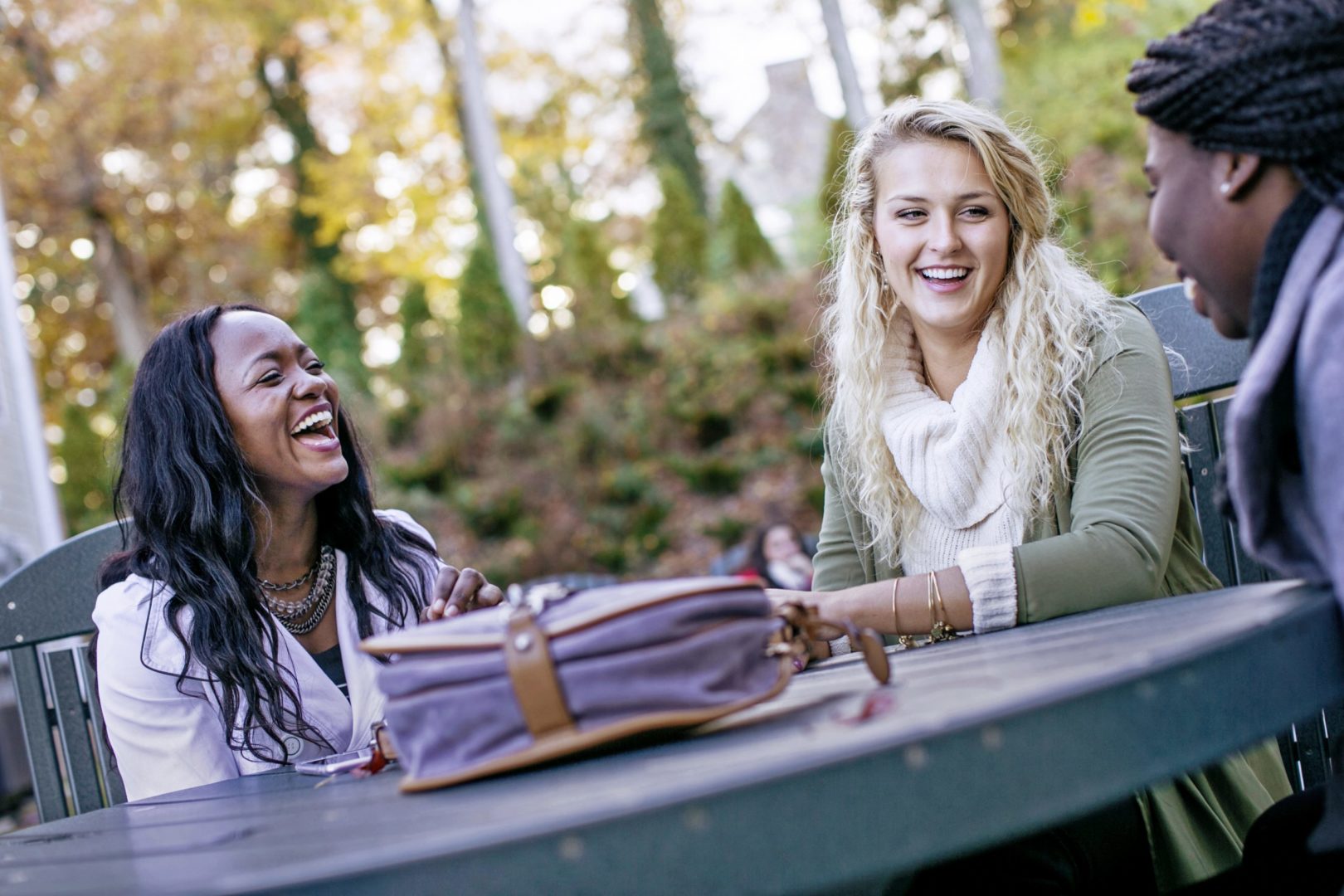 Three Bluefield University students spending time outdoors at a picnic table. 