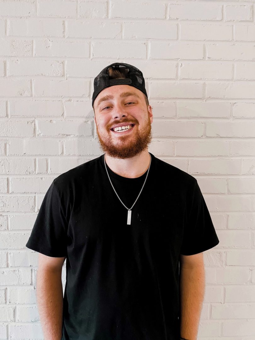 Bluefield University Campus Pastor Mason West posed in front of a white brick background.