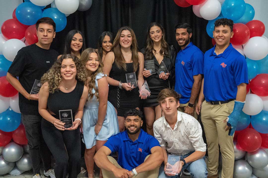 A group of students poses while holding various awards.