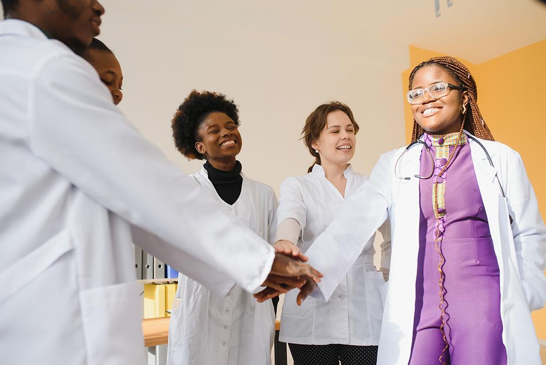 Group of medical doctors and nurses stack hands.