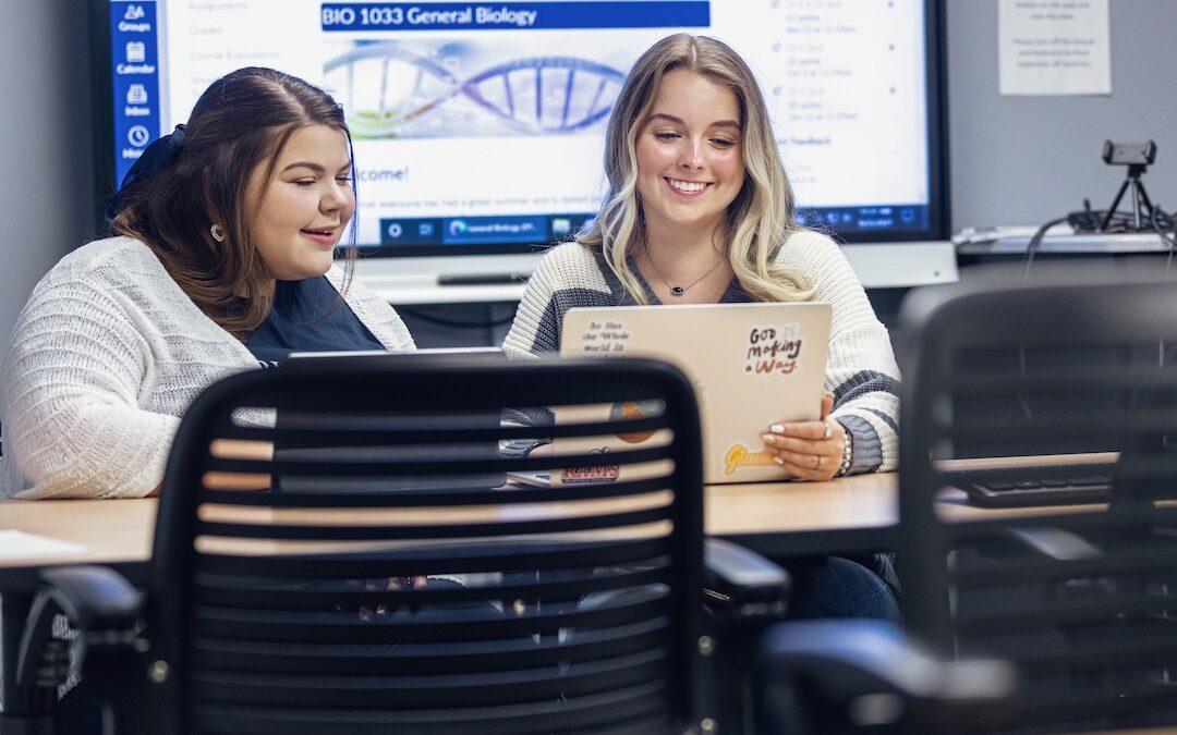 Two female students use an iPad and a laptop in Easley Library.