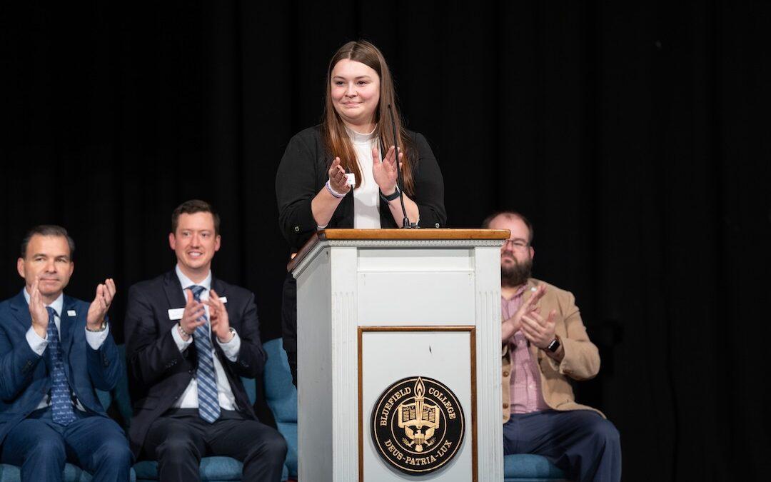 Megan Brandl leads applause for award recipients.