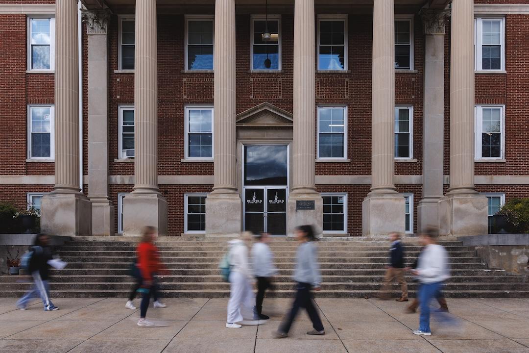 A picture of people walking in front of Lansdell Hall with motion blur.