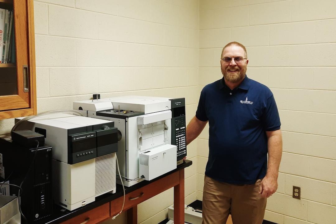 Dr. Saunders with the university's gas chromatograph-mass spectrometer.