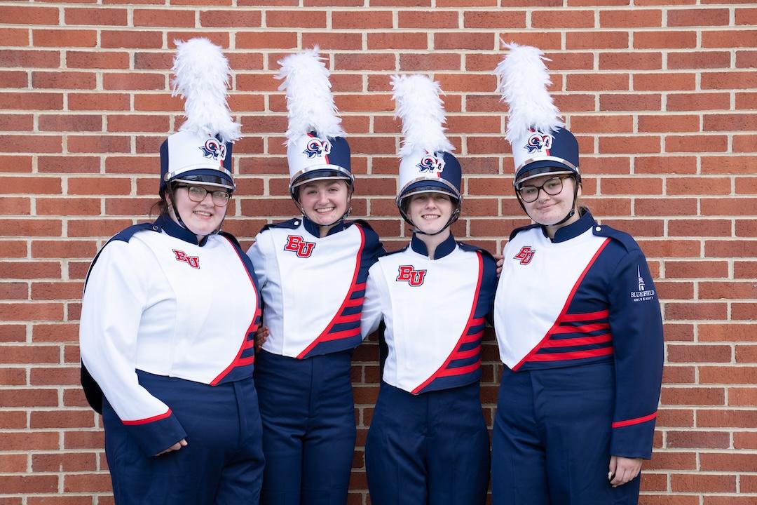 An image of four marching band members in their new uniforms.