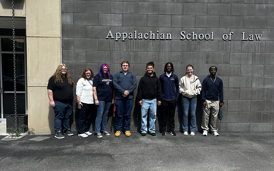 Eight students stand in front of an Appalachian School of Law sign.